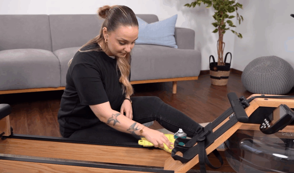 Person smører skinnen på romaskinen med cardiostrong silikonespray.