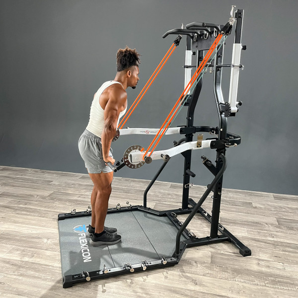 Person laver triceps pushdown med elastikker på Taurus Flexicon multimaskine i fitnessrum.